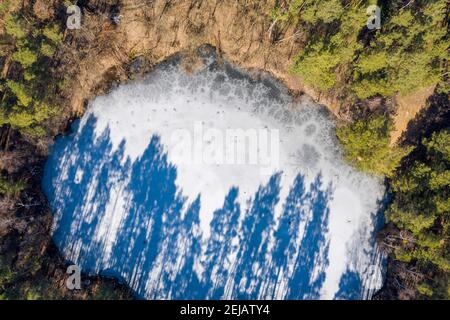 21 février 2021, Saxe-Anhalt, Schönebeck : de longues ombres d'arbres se trouvent sur le Königsee. (Photo prise avec un drone.) Le plan d'eau a été créé par l'exploitation en carrière de la roche quartzite. Le Königsee mesure 25 mètres de profondeur et est populaire auprès des plongeurs. Photo: Stephan Schulz/dpa-Zentralbild/ZB Banque D'Images