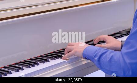 Mains d'homme jouant sur piano à queue blanc au concert - gros plan Banque D'Images