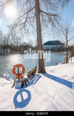 Hamm, Rhénanie-du-Nord-Westphalie, Allemagne - Ensoleillé paysage d'hiver dans la région de la Ruhr, glace et neige sur la rivière Lippe, banc de parc avec ceinture de sauvetage, dans le bac Banque D'Images