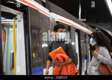 Jeune couple latin portant un masque de protection allant à l'intérieur du train, métro, métro. Nouvelle norme dans les transports publics. Banque D'Images