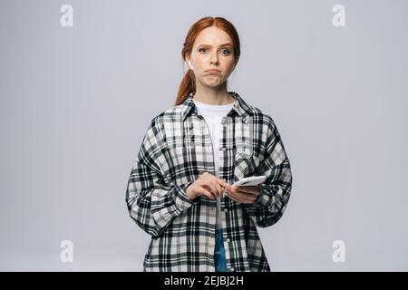 Une jeune femme douée porte des écouteurs sans fil pour taper un message en ligne arrière-plan blanc isolé Banque D'Images