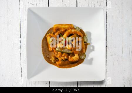 Calulu d'Angola, ragoût de poisson typique avec des légumes, jimboa, fuji polenta, okra et Chili. En blanc plaque sur fond rustique vue de dessus plat Banque D'Images