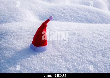 Une petite casquette de noël rouge placée sur la neige. Banque D'Images