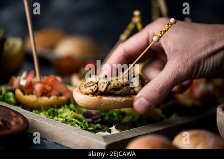 un jeune homme caucasien prend un pincho espagnol vegan d'un plateau avec quelques autres pinchos, fait avec du pain avec différentes garnitures, servi comme encas ou un Banque D'Images