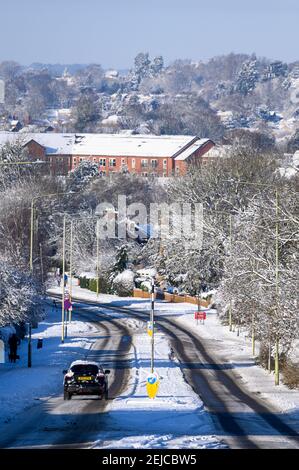 Voiture roulant sur une route enneigée par une journée d'hiver à Market Harborough, Leicestershire, Royaume-Uni. Banque D'Images