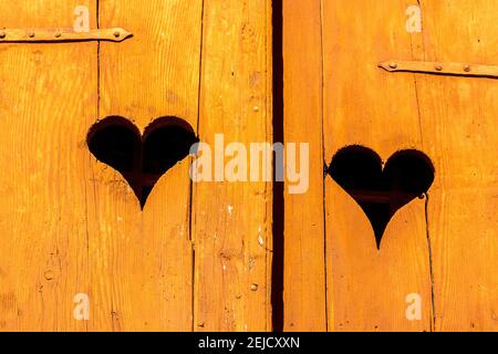 Portes rustiques en bois avec des découpes en forme de cœur dans un cadre de campagne charmant pendant la lumière du jour Banque D'Images