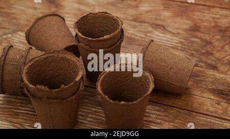 Pots de tourbe vides pour les semis sur fond de bois. Jardinage. Le concept de préparation des outils de jardin pour la plantation de printemps de plantes et de fleurs Banque D'Images