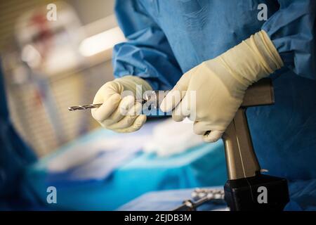 Salle d'opération : infirmière préparant un exercice pour l'installation d'une prothèse de genou (chirurgie orthopédique). Banque D'Images