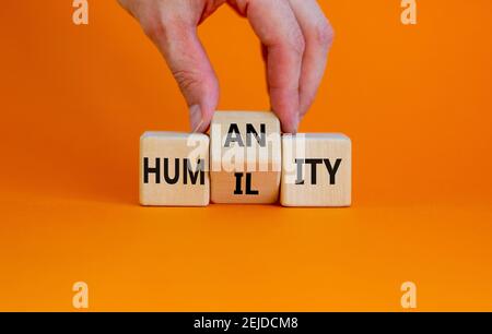 Humilité contre symbole de l'humanité. L'homme d'affaires transforme les cubes et transforme le mot « humilité » en « humanité ». Belle table orange, fond orange, copie sp Banque D'Images