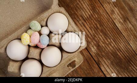 Œufs de poulet dans un plateau en carton et décor de Pâques sur fond de bois., style rural Banque D'Images