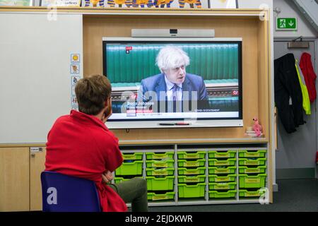 Un enseignant de l'école primaire de sexe masculin assis dans sa salle de classe en regardant le Premier ministre Boris Johnson sur la salle de classe interactive SMART board annoncer que les écoles doivent rouvrir à tous les écoliers en Angleterre à partir du 8 mars.Londres, Royaume-Uni 22 février 2021. Banque D'Images