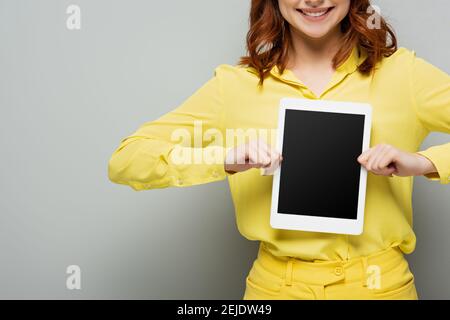 vue rognée d'une femme joyeuse montrant une tablette numérique vierge écran en gris Banque D'Images