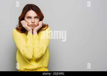 une femme offusque elle regarde vers le haut tout en tenant les mains près du visage gris Banque D'Images