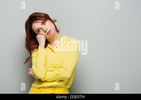 triste femme regardant loin en se tenant avec la main près du visage en gris Banque D'Images