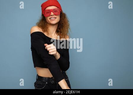 Photo prise de belle jeune heureuse blonde sombre femme porter vêtements décontractés bandana rouge et lunettes de soleil stylées isolées sur coloré arrière-plan Banque D'Images