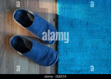 Pantoufles en feutre bleu à la maison devant la moquette Banque D'Images