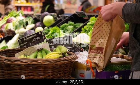 Une personne ramassant des légumes dans un sac de papier dans le petit magasin d'aliments biologiques local qui offre une sélection de légumes locaux de la ferme. Banque D'Images