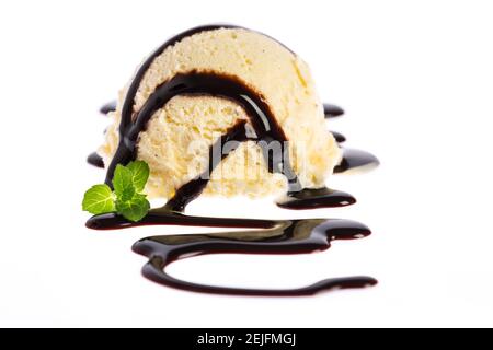 Cuillère à crème glacée à la vanille avec garniture au chocolat et un petit feuille de menthe isolée sur fond blanc Banque D'Images