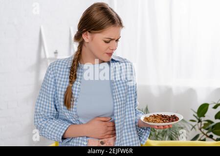 Contrarié femme avec allergie regardant l'assiette avec des noix Banque D'Images