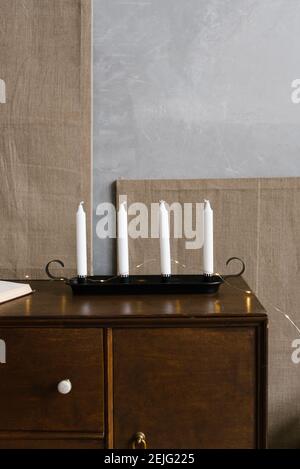 Bougies fines blanches sur un support de chandelier noir sur une commode en bois marron. Éléments de décoration néo-classique ou d'intérieur vintage Banque D'Images