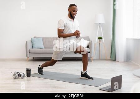 African American Guy Doing Forward Lunge entraînement à la maison Banque D'Images