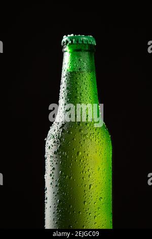 Fermez la bouteille de bière froide avec une goutte d'eau isolée sur fond noir. Format vertical. Banque D'Images
