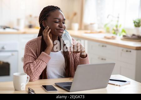 Portrait de la jeune femme noire qui se grattent le visage après avoir porté un médecin Masque Banque D'Images