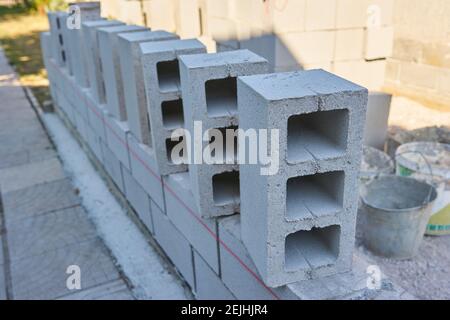 un travailleur construit un mur de blocs de cinder pour un nouveau accueil Banque D'Images