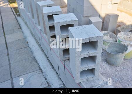 un travailleur construit un mur de blocs de cinder pour un nouveau accueil Banque D'Images