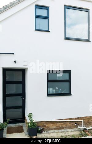 Une maison moderne typique qui a été rénovée avec un rendu blanc et des fenêtres et des portes en plastique UPVC gris foncé à double vitrage. Banque D'Images