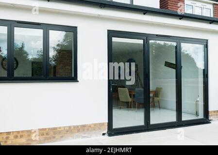 Une maison moderne typique qui a été rénovée avec un rendu blanc et des fenêtres et des portes en plastique UPVC gris foncé à double vitrage. Banque D'Images