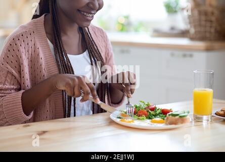 Heure du petit déjeuner. Happy African American Lady manger un savoureux repas sain dans la cuisine Banque D'Images