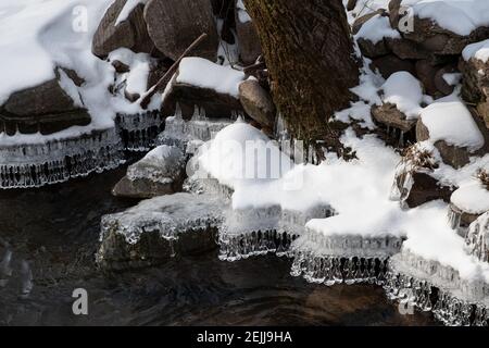 Des formes de glace en cristal étonnantes suspendues au bord de la neige rive couverte pendant l'hiver Banque D'Images