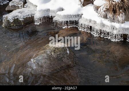 Des formes de glace en cristal étonnantes suspendues au bord de la neige rive couverte pendant l'hiver Banque D'Images