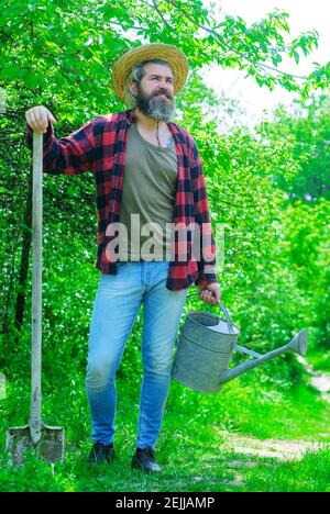 Ferme. Homme souriant avec arrosoir et pelle. Agriculteur se préparant à la plantation. Jardinage. Pelle de jardin. Banque D'Images