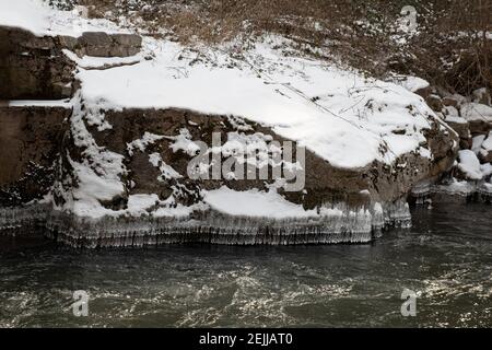 Des formes de glace en cristal étonnantes suspendues au bord de la neige rive couverte pendant l'hiver Banque D'Images