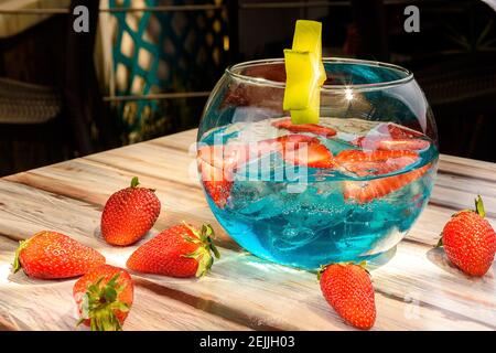 Gros plan d'une boisson bleue avec des fraises servies dans un bol à poisson en verre Banque D'Images