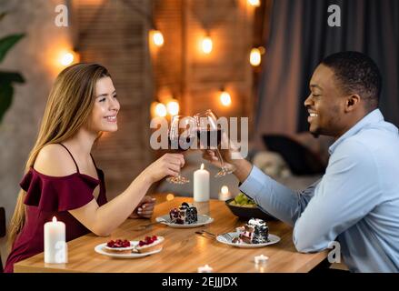 Romantique couple multiethnique clinking verres avec vin le jour de l'arrivée Restaurant Banque D'Images