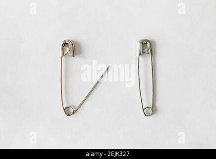 Deux broches de sécurité argentées sur fond blanc, une broche de sécurité ouverte à gauche, une broche de sécurité fermée à droite Banque D'Images