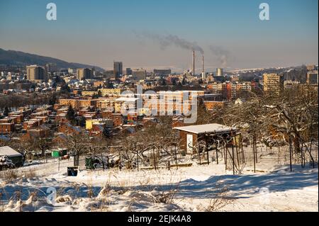 Vue sur la ville de Zlin et la périphérie enneigée avec des maisons en briques rouges typiques et une cheminée de chauffage en arrière-plan. République tchèque. Banque D'Images