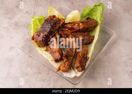 Plaque de côtes de porc chaudes préparée sur le gril avec Sauce barbecue sur un lit de laitue fraîche Banque D'Images