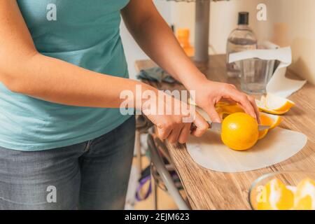Femme dans sa cuisine coupant des fruits délicieux pour préparer un jus Banque D'Images