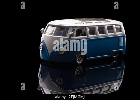 Gros plan d'un jouet bleu de mini van avec des reflets étonnants. Tir sur fond noir et acrylique réfléchissant Banque D'Images