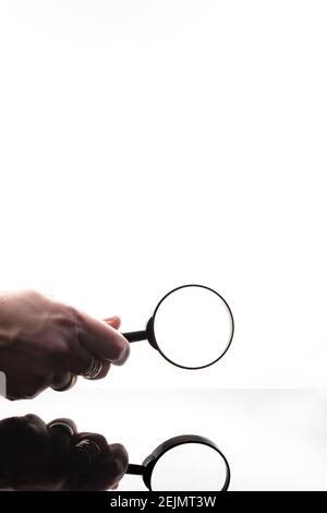 Gros plan d'une main de femme tenant la loupe. Prise de vue isolée sur fond blanc parfait avec des reflets étonnants. Équipement parfait pour les bureaux Banque D'Images