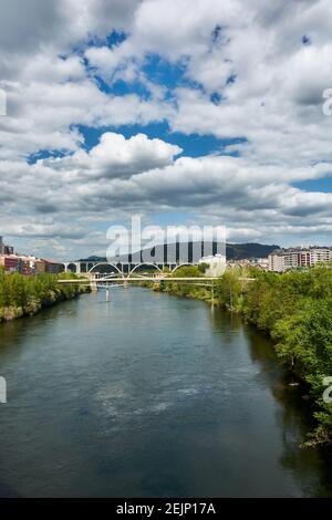 Ville d'Ourense en Galice, Espagne. Vue sur la rivière Minho depuis le pont romain sous un magnifique ciel bleu ciel nuageux le jour du printemps. Tir vertical. Banque D'Images