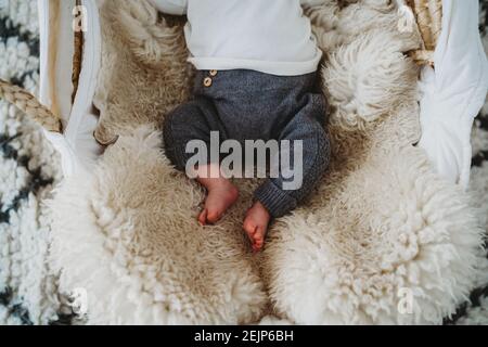 Vue de dessus des pieds de bébé nouveau-né dans le panier avec des moutons tapis de peau Banque D'Images