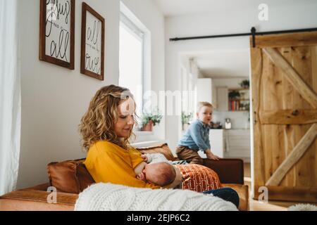 Mère allaitant bébé nouveau-né à la maison dans la chambre familiale avec fils Banque D'Images