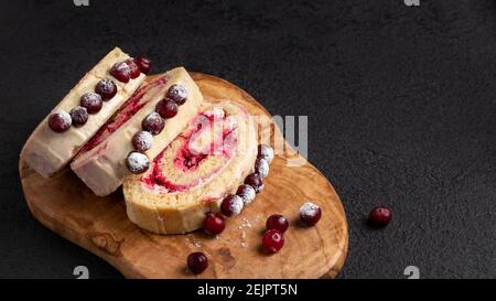 Biscuit maison, roulé sucré avec canneberges et crème sur une table noire, espace copie. Banque D'Images