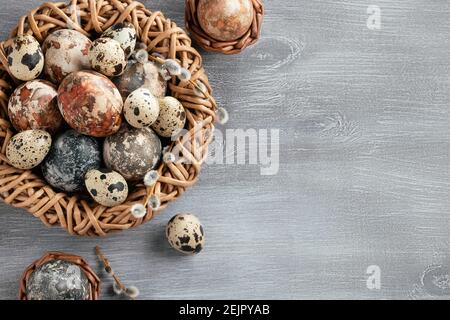 Composition Pâques - plusieurs œufs en marbre peints avec des teintures naturelles dans un nid et des paniers en osier, vue du dessus. Banque D'Images