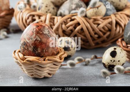 Composition de Pâques - plusieurs oeufs en marbre peints avec des teintures naturelles dans un nid en osier et des paniers. Banque D'Images